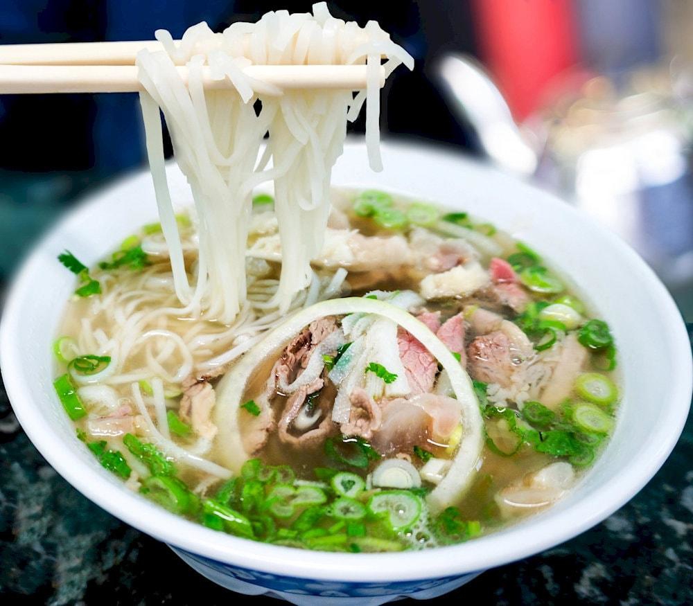 A steaming bowl of traditional pho in Hanoi, served with rice noodles, herbs, and tender slices of beef or chicken – a true taste of Vietnam